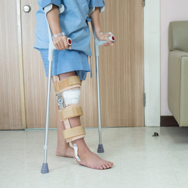 Asian woman patient with knee brace with walking stick and knee